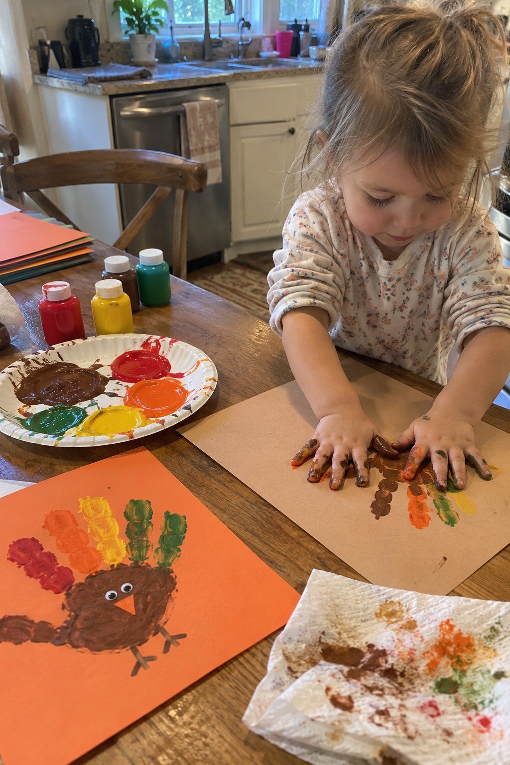 Easy handprint turkey painting toddler Thanksgiving craft on a kitchen table